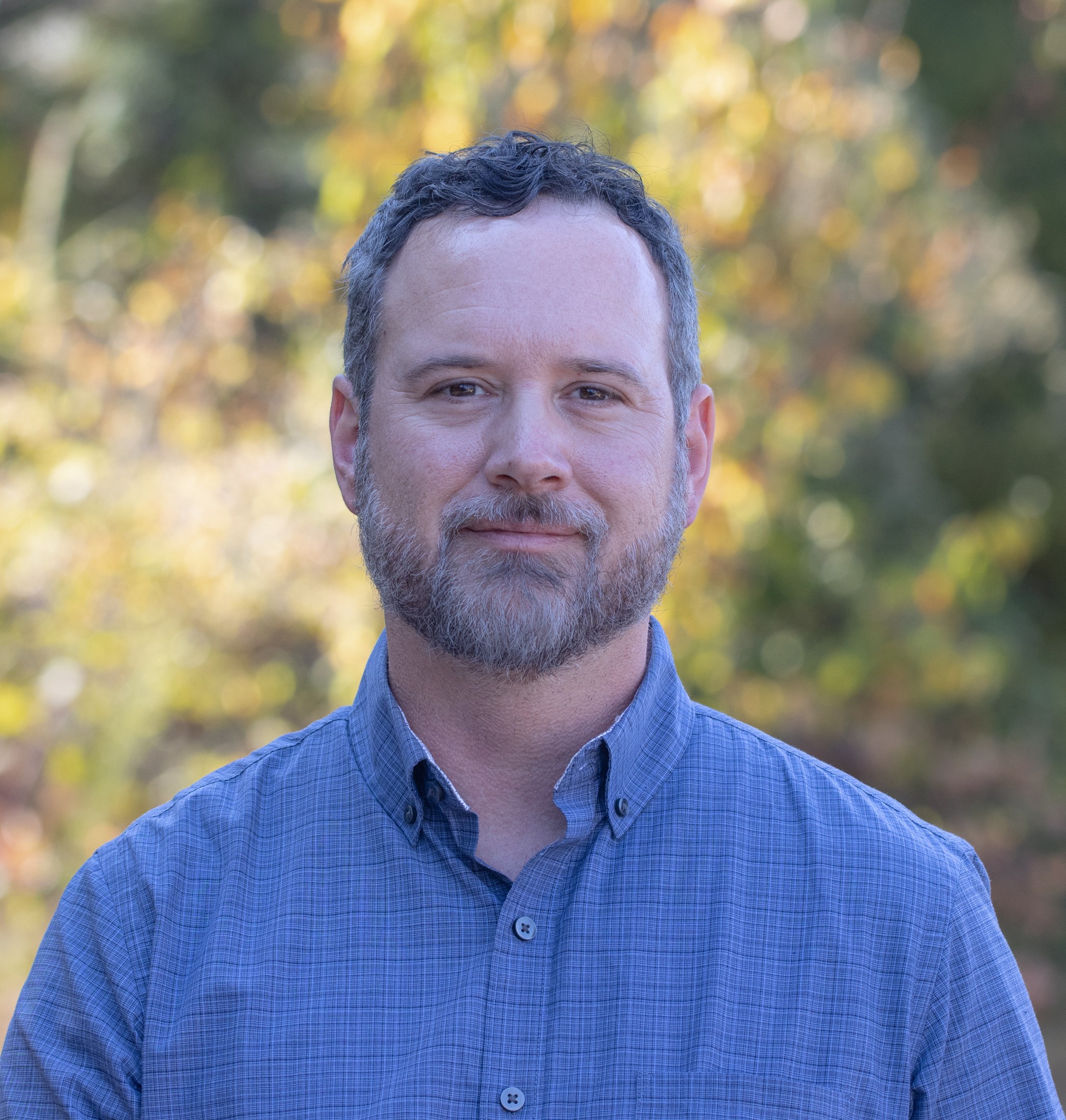 Joe Dlugo, a man in his forties with graying hair and a beard with a neutral expression