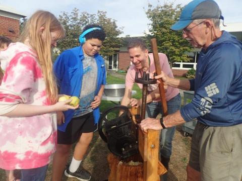Makayla, Kayden and Bill watching Kevin spin the cider press wheel