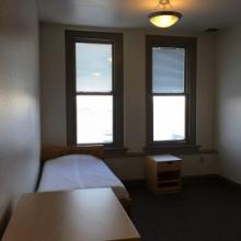 a dorm room with two windows to the outside