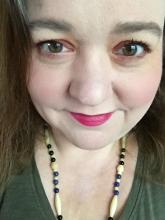 Headshot of Jennifer, a female, green eyes and brown hair wearing green with a necklace.