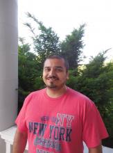 Amador Madrigal, a Hispanic American man with a Gap teeth smile with a red shirt and short dark brown hair, outside of WSSB. 