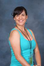 JoAnne Fink, an olive skinned, dark haired woman with bangs swept to the side smiling at the camera.