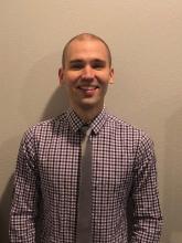 Kyle Smelter, A young adult man wearing a button-down shirt and short hair standing next to a wall and smiling