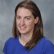 woman with straight mid length  dirty blond hair who is wearing a royal blue shirt with hazel eyes.