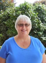 Karen Quillard, short gray haired woman with  glasses, smiling, and showing dimples.  
