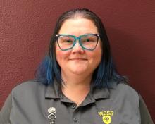 Headshot of Amanda Rodda with blue hair, blue sparkle glasses and a grey polo shirt with yellow WSSB lion logo on the pocket.