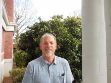 Outdoor headshot of Carl Talley, a middle aged man with a gray beard, thinning hair and a friendly smile.