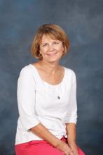 Cindy McAlexander,  a middle-aged woman with medium length dark blond hair, green eyes and caring smile.