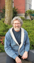 Richard, a smiling gentleman with wavy brown hair, wire-rimmed glasses, and a graying goatee in a blue fleece-lined hoody