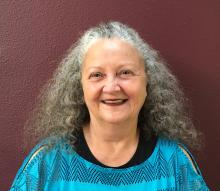 Tina Powell, a gracefully aging woman with sparkling blue eyes and grayish/brown curly hair. 