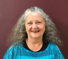 Tina Powell, a gracefully aging woman with sparkling blue eyes and grayish/brown curly hair.