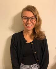 Jessica Chandler, a woman with long brown hair, smiling and wearing a black sweater and glasses.