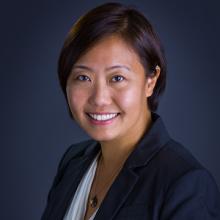 Yue-Ting, a medium skin-toned female of Chinese descent smiles at the camera. She wears a white scoop neck top under a navy blazer.