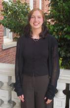 Autumn standing outside of the Old Main building smiling